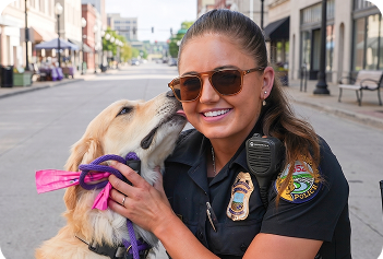 Dog licking the face of a woman in a police uniform