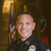 police officer in uniform smiling with american flag in background