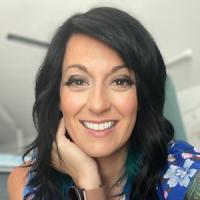Rachel Dooley Woman with black hair smiling at camera against a white background