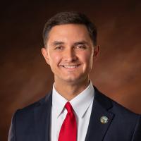 Jeff Davis white male in blue suit and red tie in front of brown background