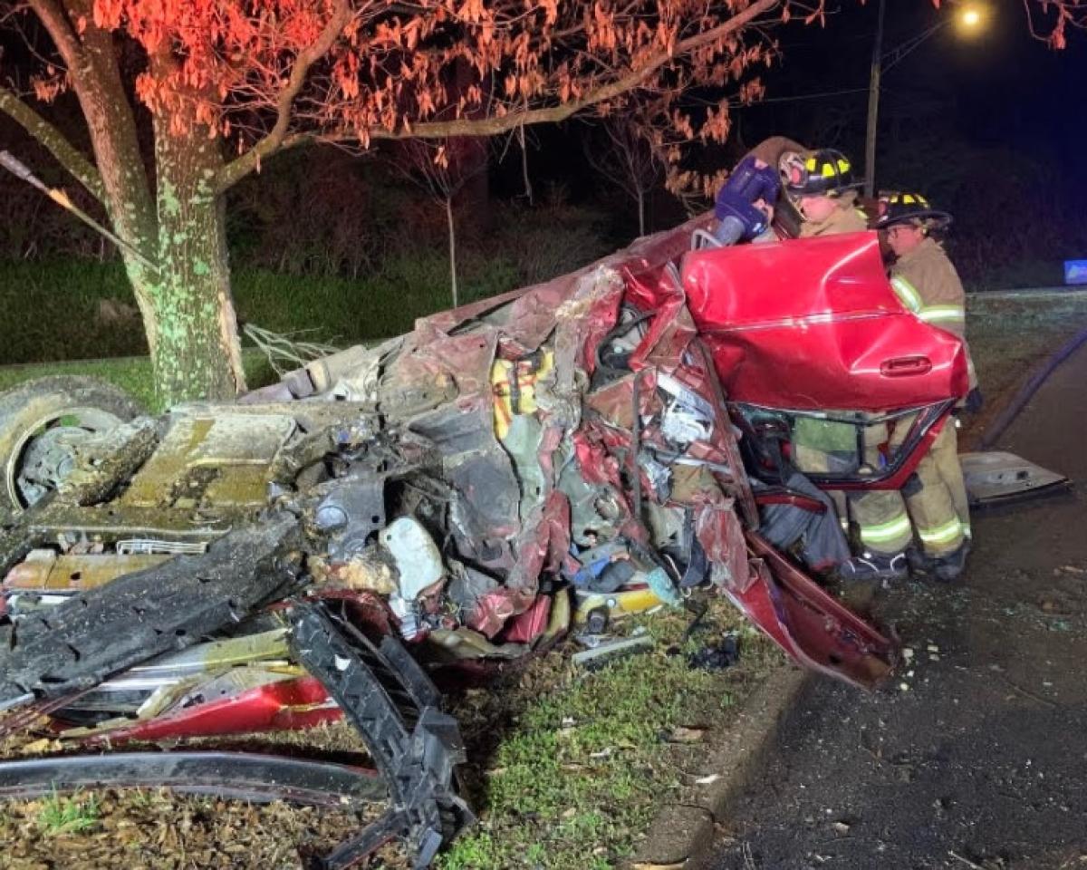 A crashed car on the side of the road, with fire department personnel performing an extraction.