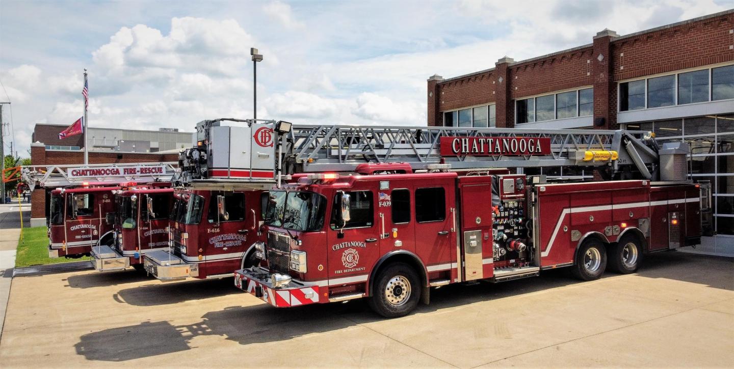  Three red fire trucks parked in front of a building at fire station 1.