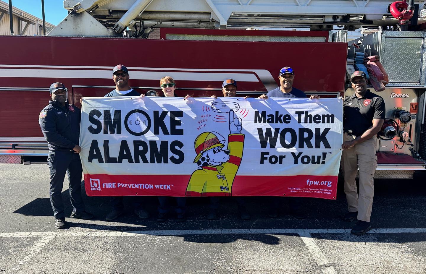 Fire fighters holding sign about smoke alarms