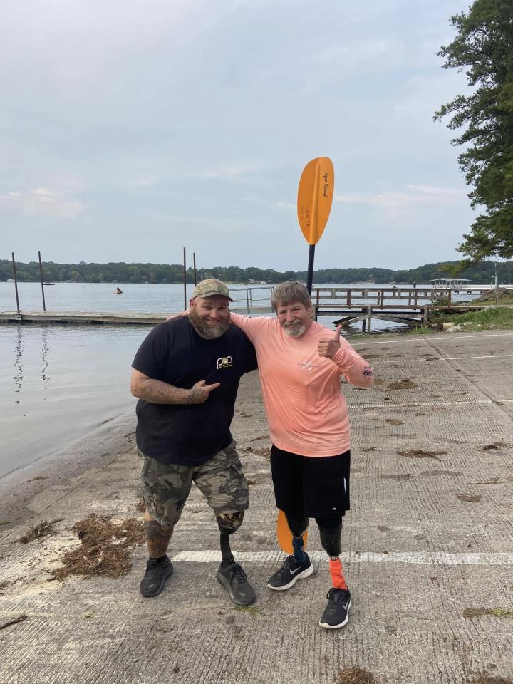 Dos hombres junto al lago posando para una foto.