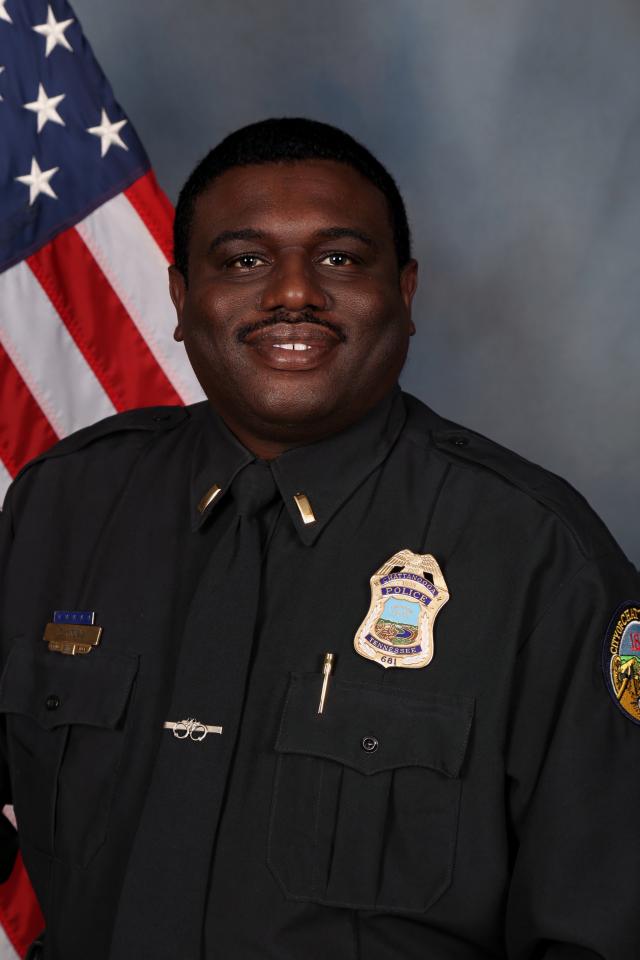 Police officer posing for camera with American flag behind him