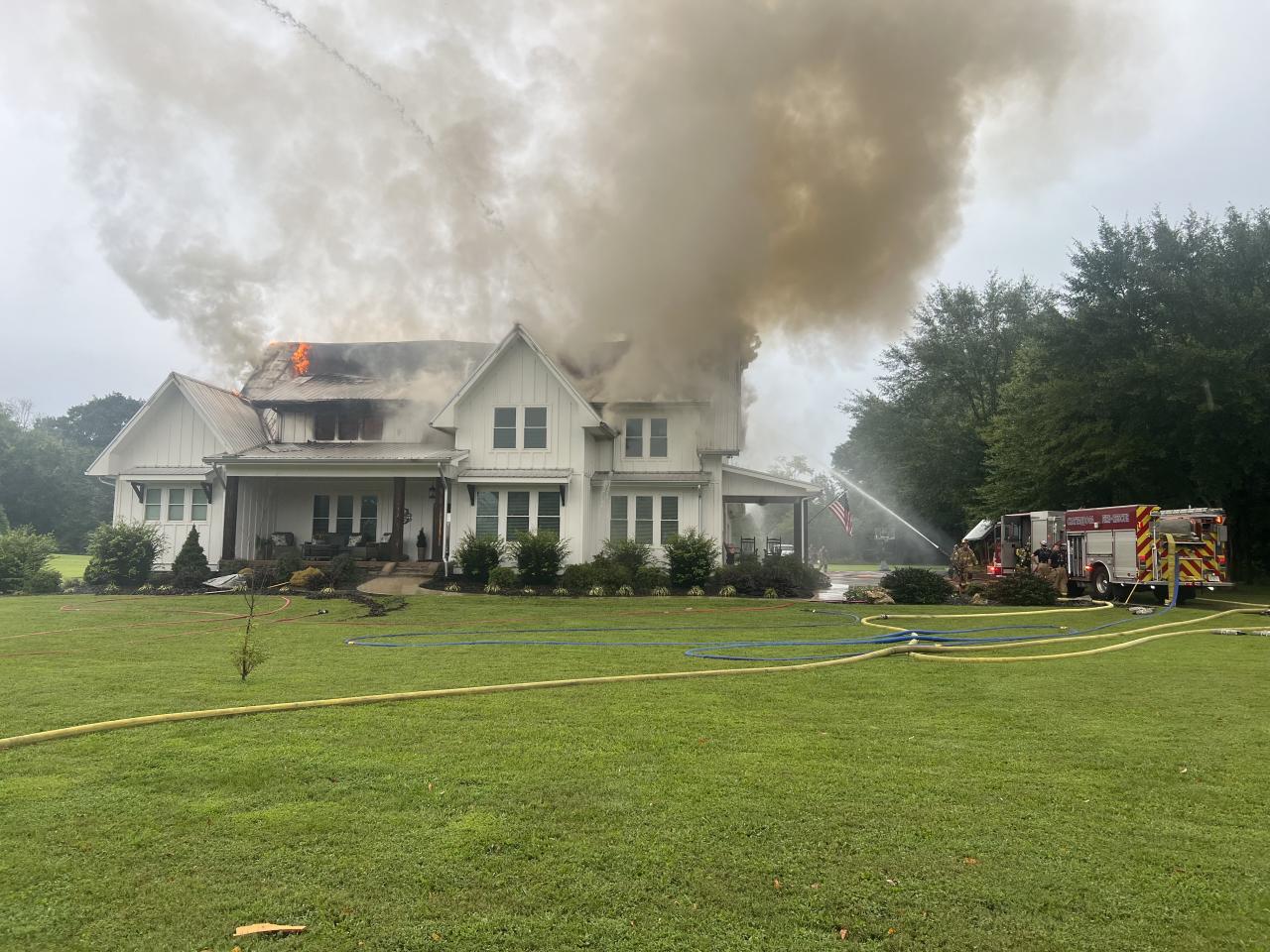 Humo saliendo de la casa mientras los bomberos intentan apagarlo.