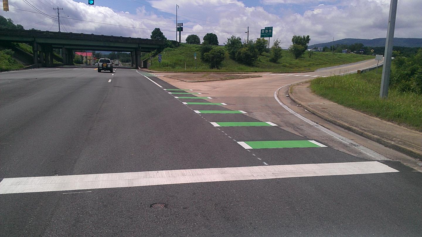 A road with green marking stripes guiding cyclists through intersections, ensuring safety for all road users.