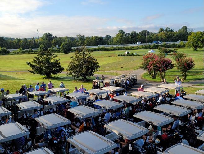 Several golf carts parked on grass at Brown Acres golf course.