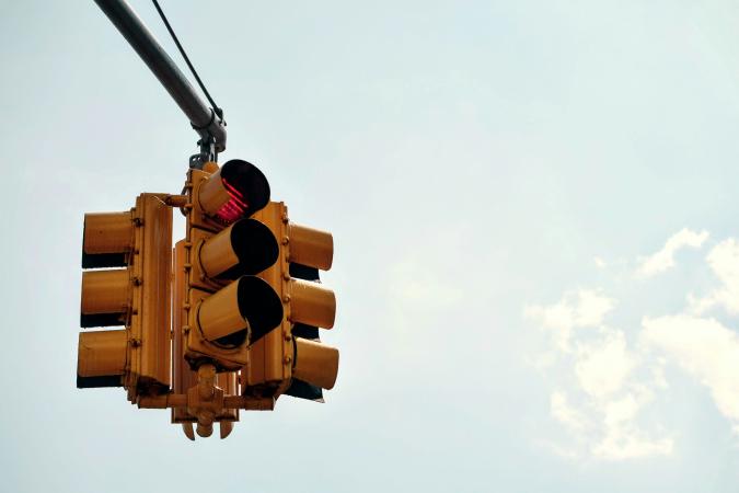 A traffic light showing a red signal against a clear sky, symbolizing traffic tickets, citations, and fines.