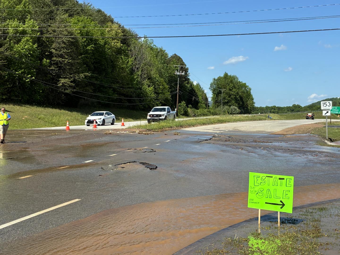 Water flowing over road next to estate sale sign