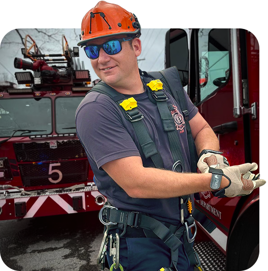 A Chattanooga Fireman putting his work gloves on in front of two fire engines.