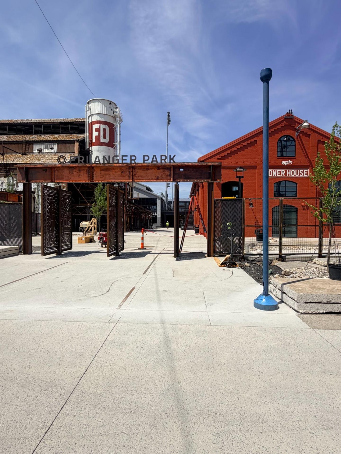 Entrance to Erlanger Park showing industrial architecture, a red brick power house, and a white water tower with red lettering.