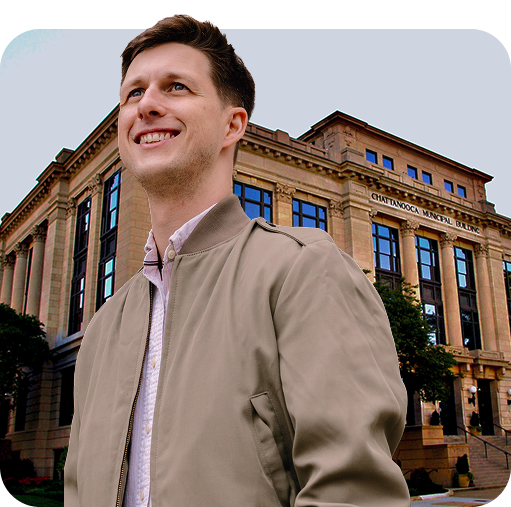 A young business professional in front of Chattanooga's City Hall building.