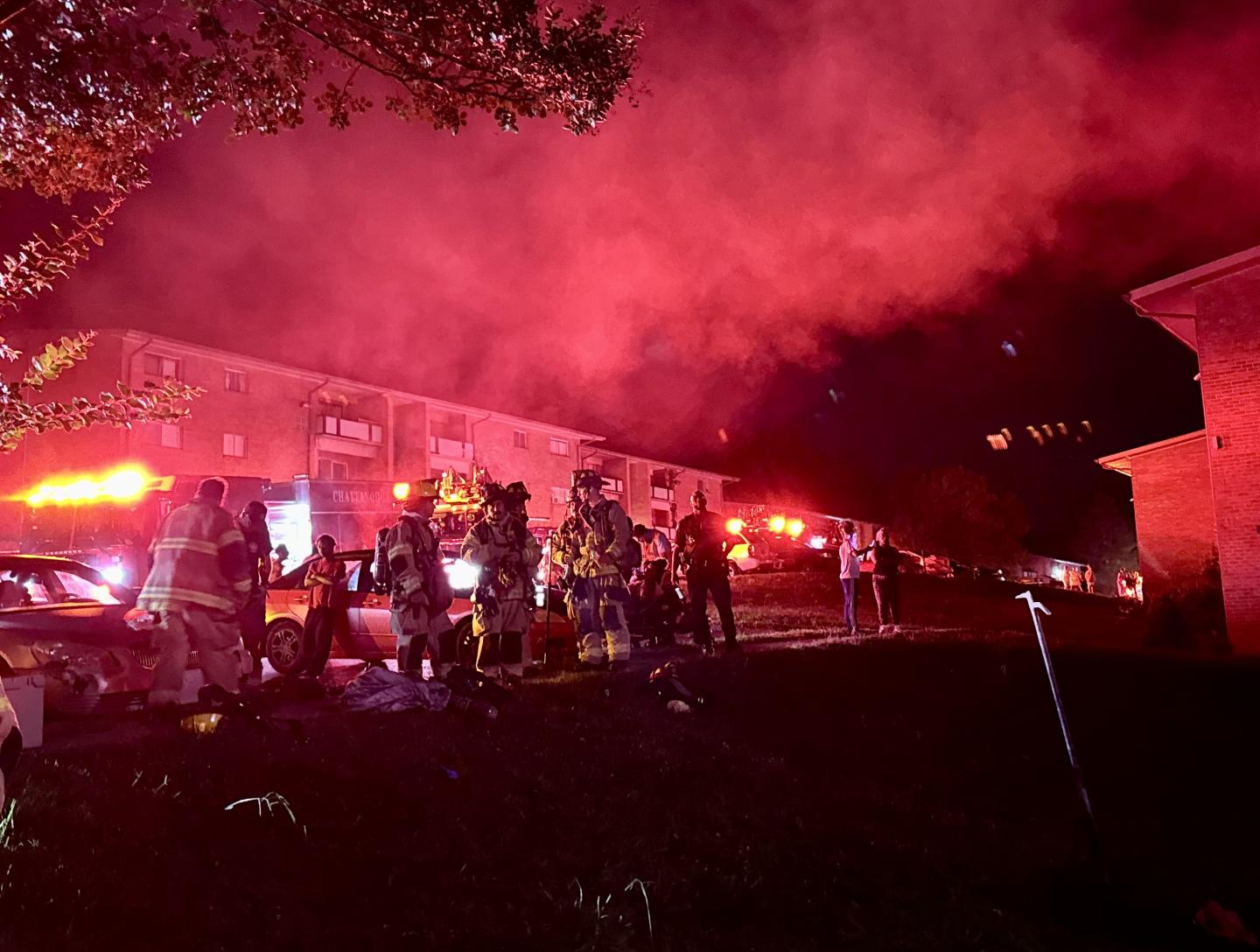 Firefighters standing outside building with smoke in the background