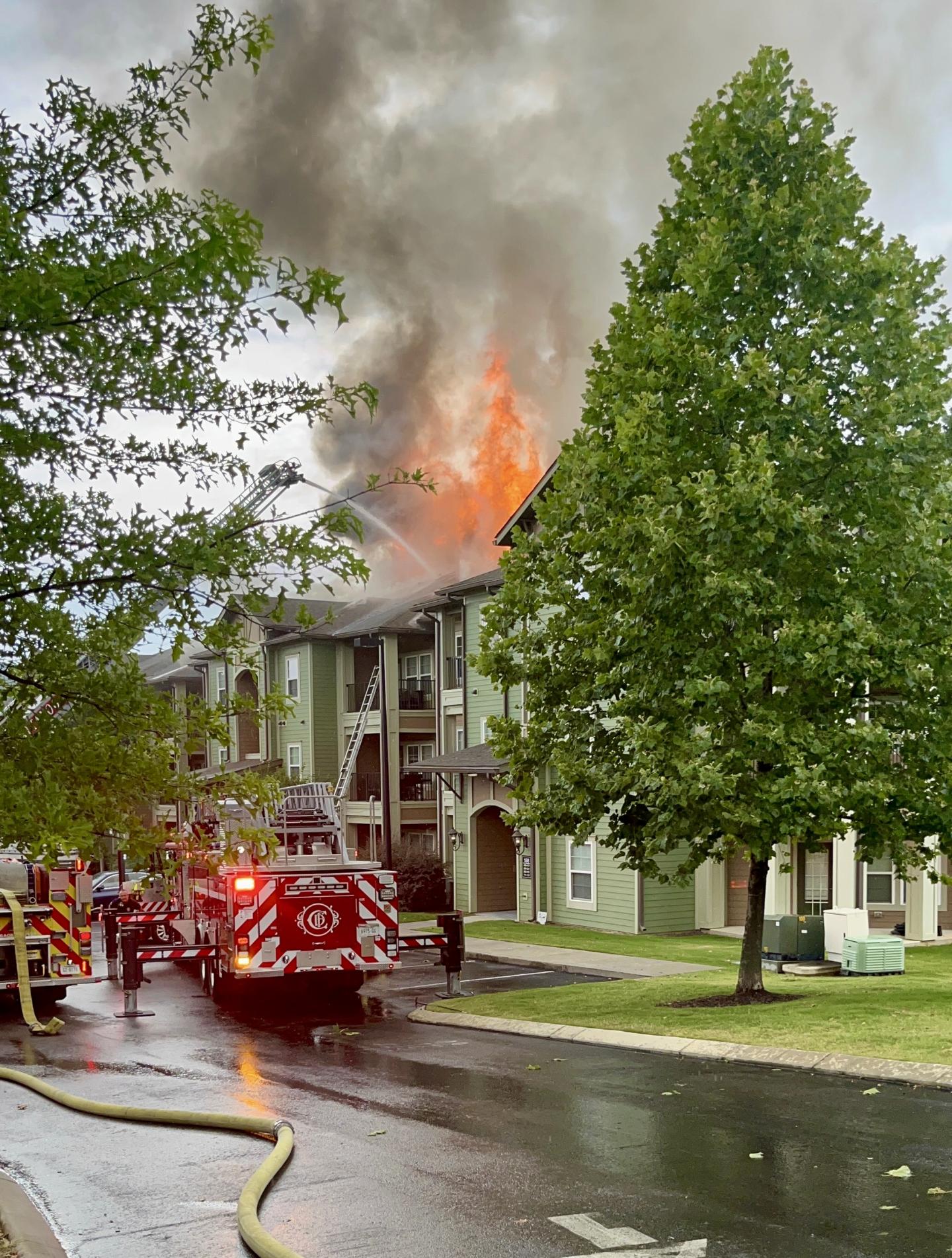 Apartment building on fire, with fire truck spraying water on it